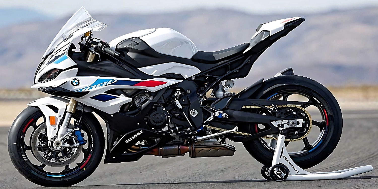 The 2023 BMW S 1000RR motorcycle in a sleek blue and white color scheme, safely parked on a racing track stand with its back wheel suspended in the air.