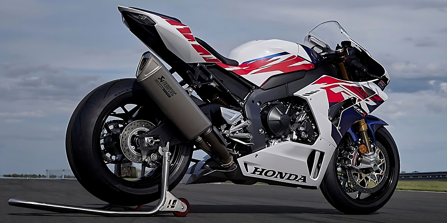 The 2023 Honda CBR1000RR-R Fireblade SP motorcycle in a sleek white, red, and blue color scheme, parked on a silver racing track stand with its back wheel elevated.