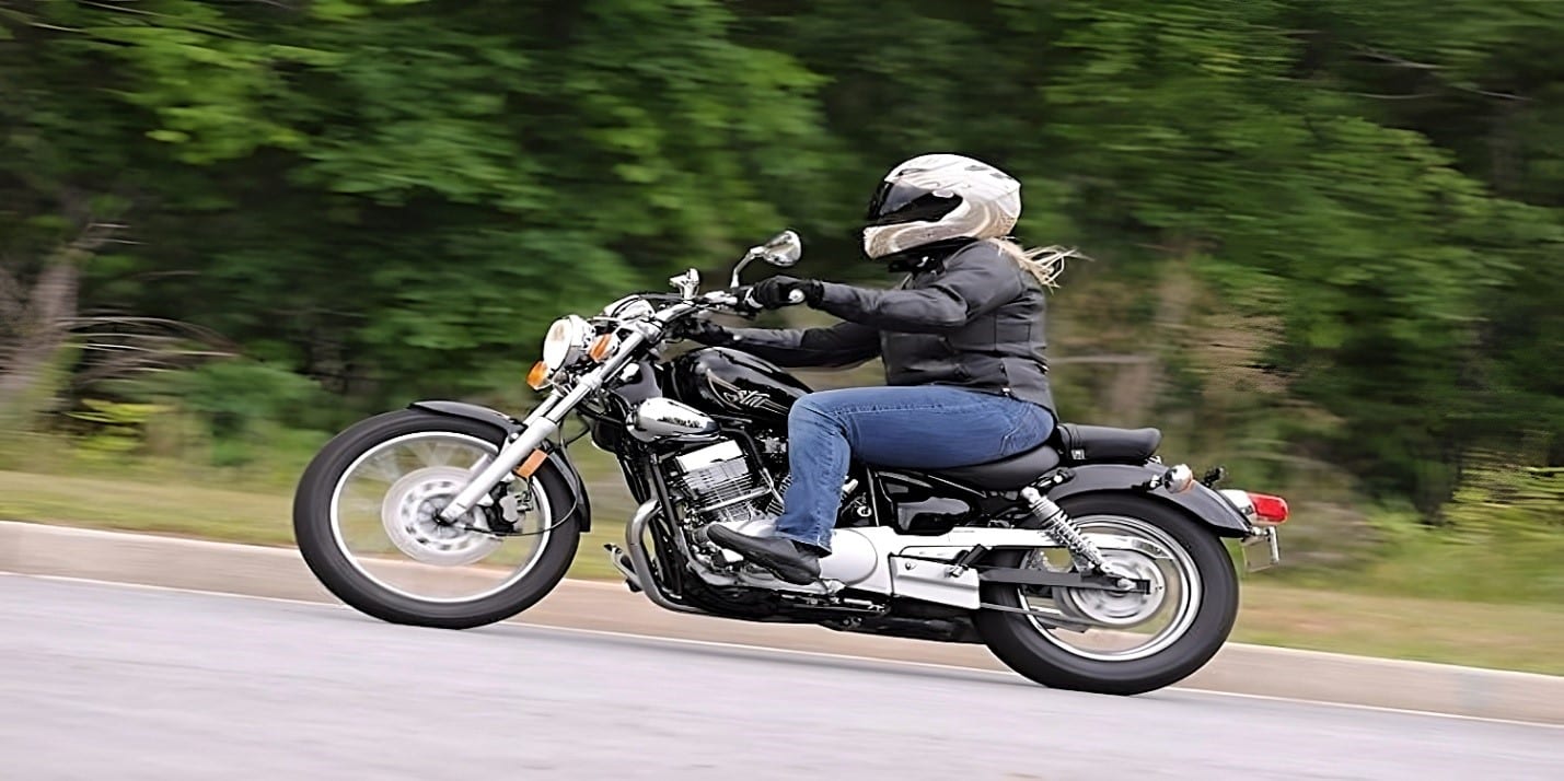 A female rider in blue jeans effortlessly navigating a steep hill on a black Yamaha V Star 250 motorcycle. The V Star 250 confidence-inspiring, the simple-to-ride platform for beginning riders, and the low seat height of 27 inches (a full 2 inches less than the Kawasaki Ninja 250) have a lot to do with the fact that this bike was clearly designed for highway cruising with shorter and female riders in mind.