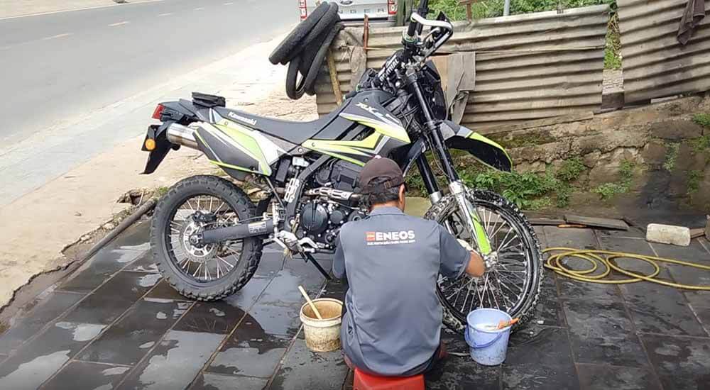 Using two buckets, one for the cleaning solution and one with clean water for rinsing. To the side, a garden horse, which can also rinse the motorcycle with the correct attachments.