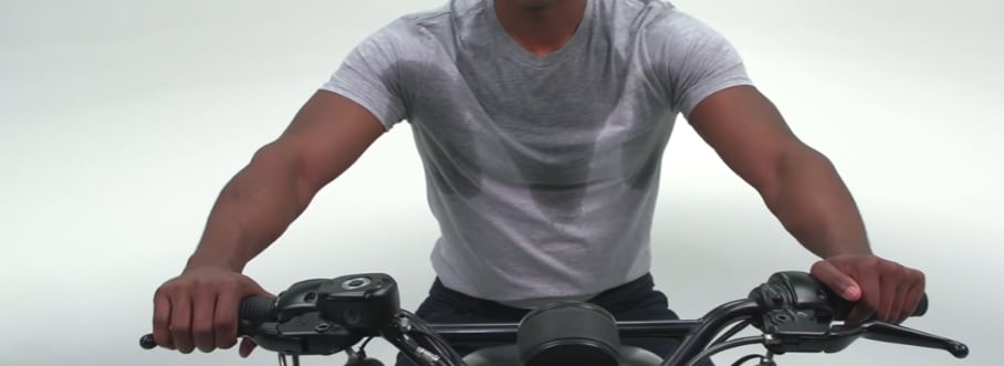 A rider is sweating profusely onto an ordinary T-shirt without moisture-wicking and quick-dry properties, causing him discomfort and distracted riding.