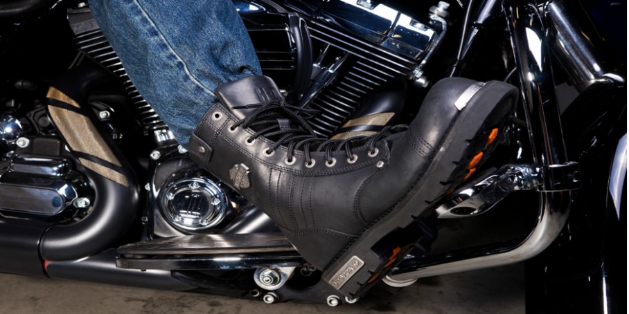 A pants tucker with their jeans tucked into their motorcycle boots enjoys their ride.