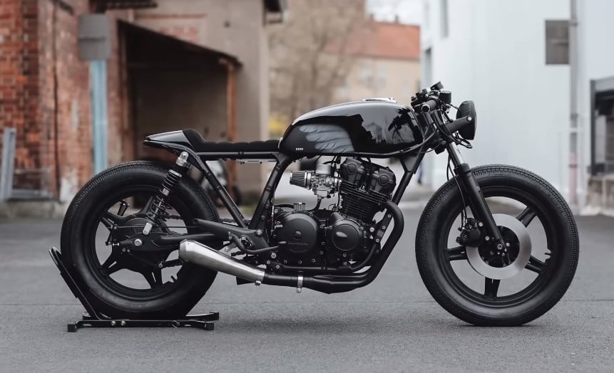 A black Hookie’s Evil 'Crow' Honda CB750 Cafe Racer on a motorcycle rear wheel stand, showcased on a street.